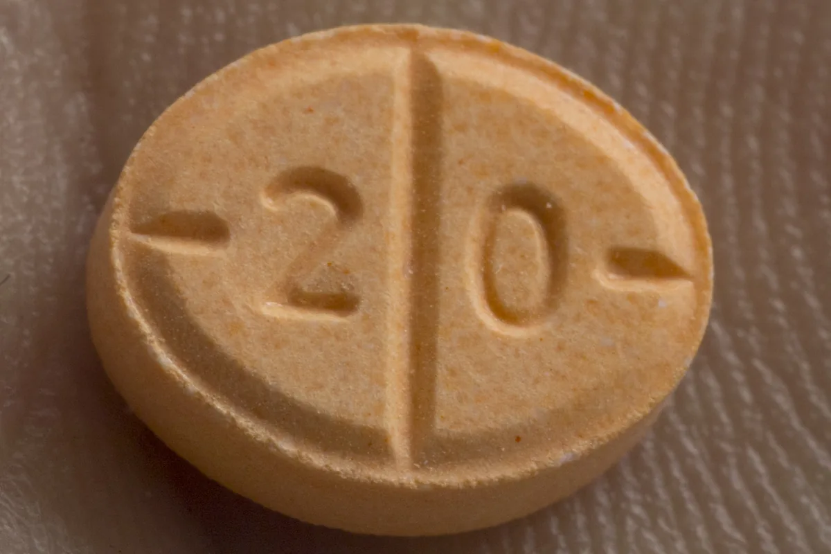 Close-up of a single orange Adderall tablet scored down the middle and stamped with the number 2 0