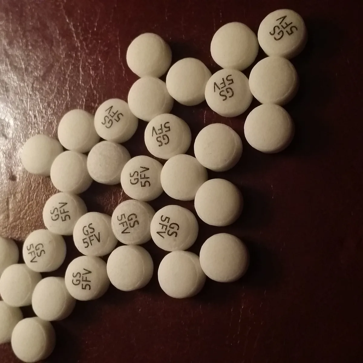 Round off-white bupropion 150 mg extended-release tablets sold as Elontril, scattered on a dark wooden surface