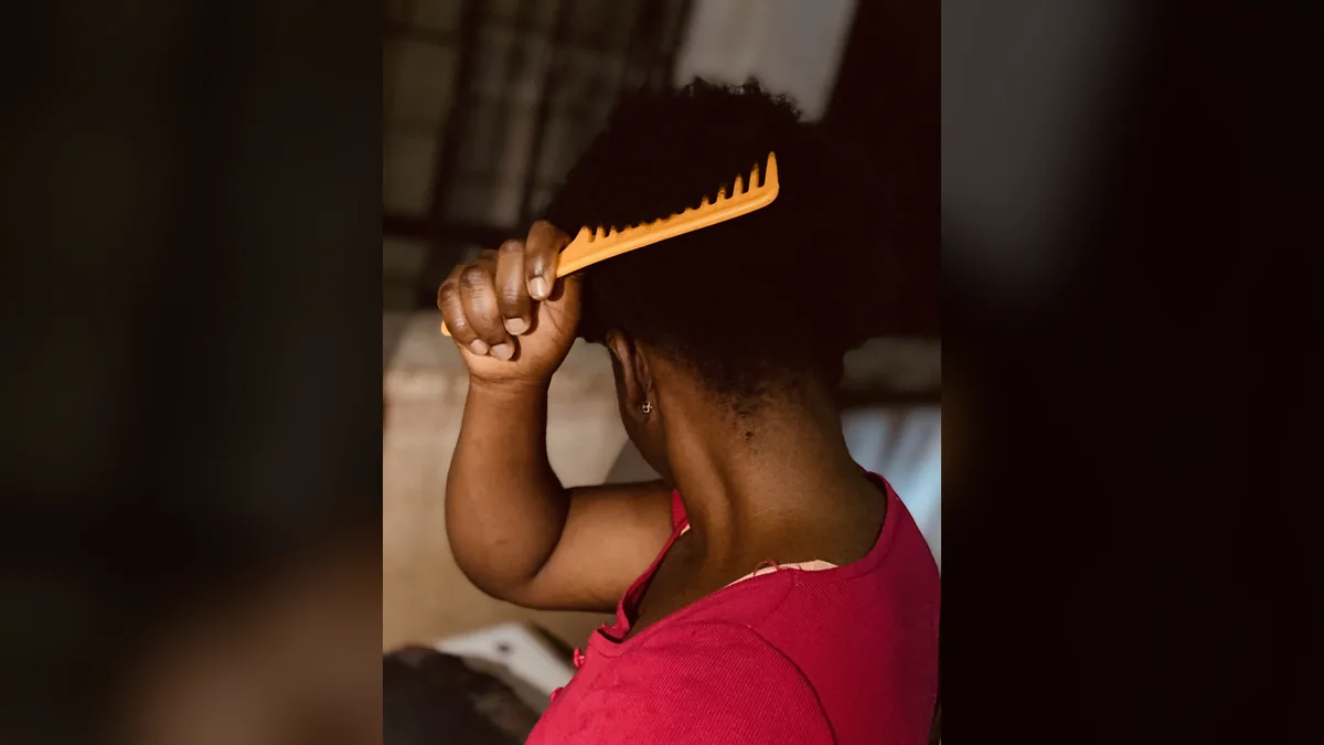 Femme peignant ses cheveux afro courts avec un peigne orange à dents larges