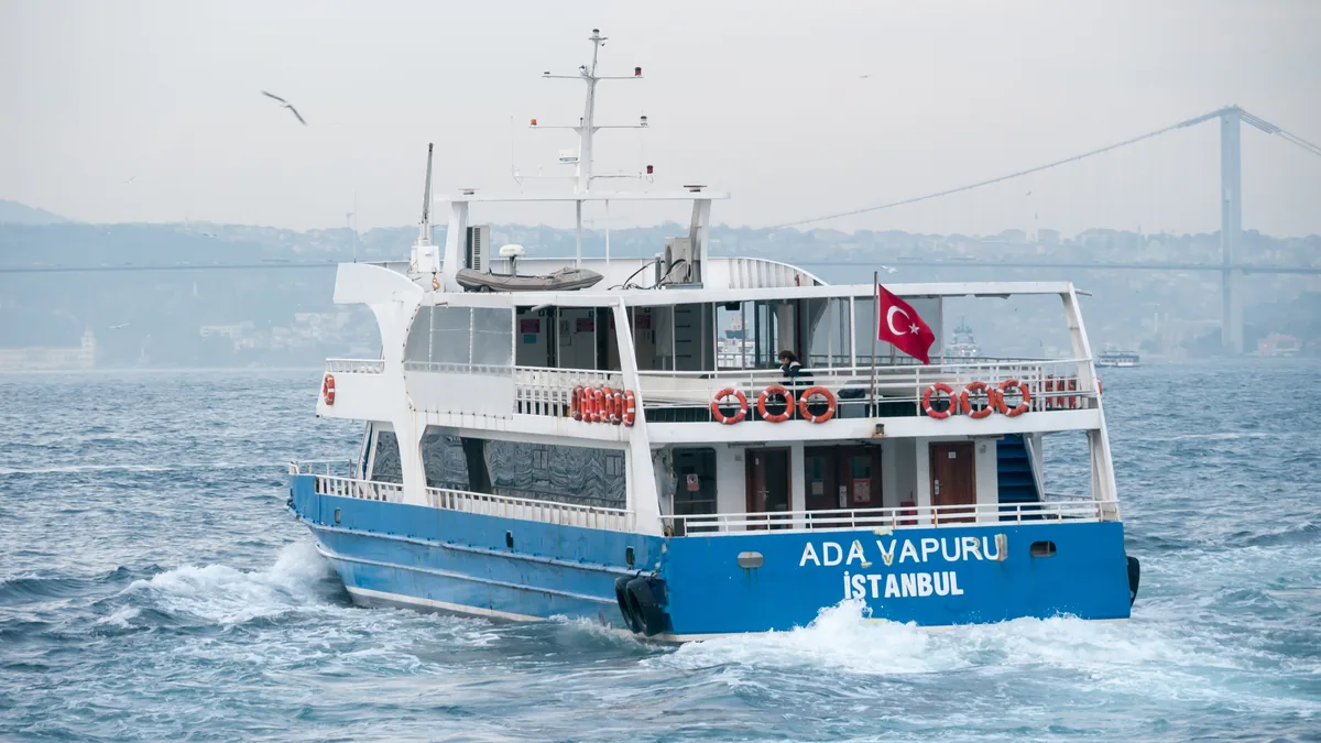 A passenger ferry crossing the Bosphorus strait in Istanbul, with the city shoreline behind it
