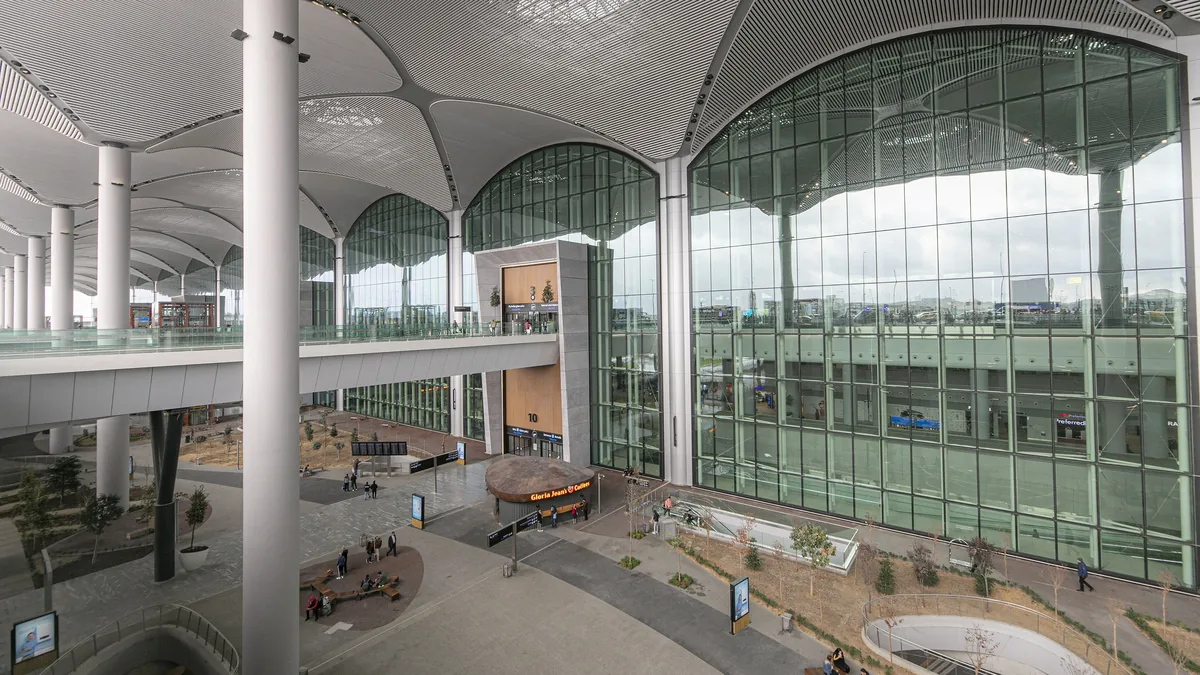 Tall glass facade and roof canopy seen from inside the Istanbul Airport terminal