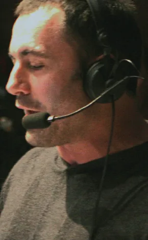 Joe Rogan commentating at a UFC event with short cropped dark hair