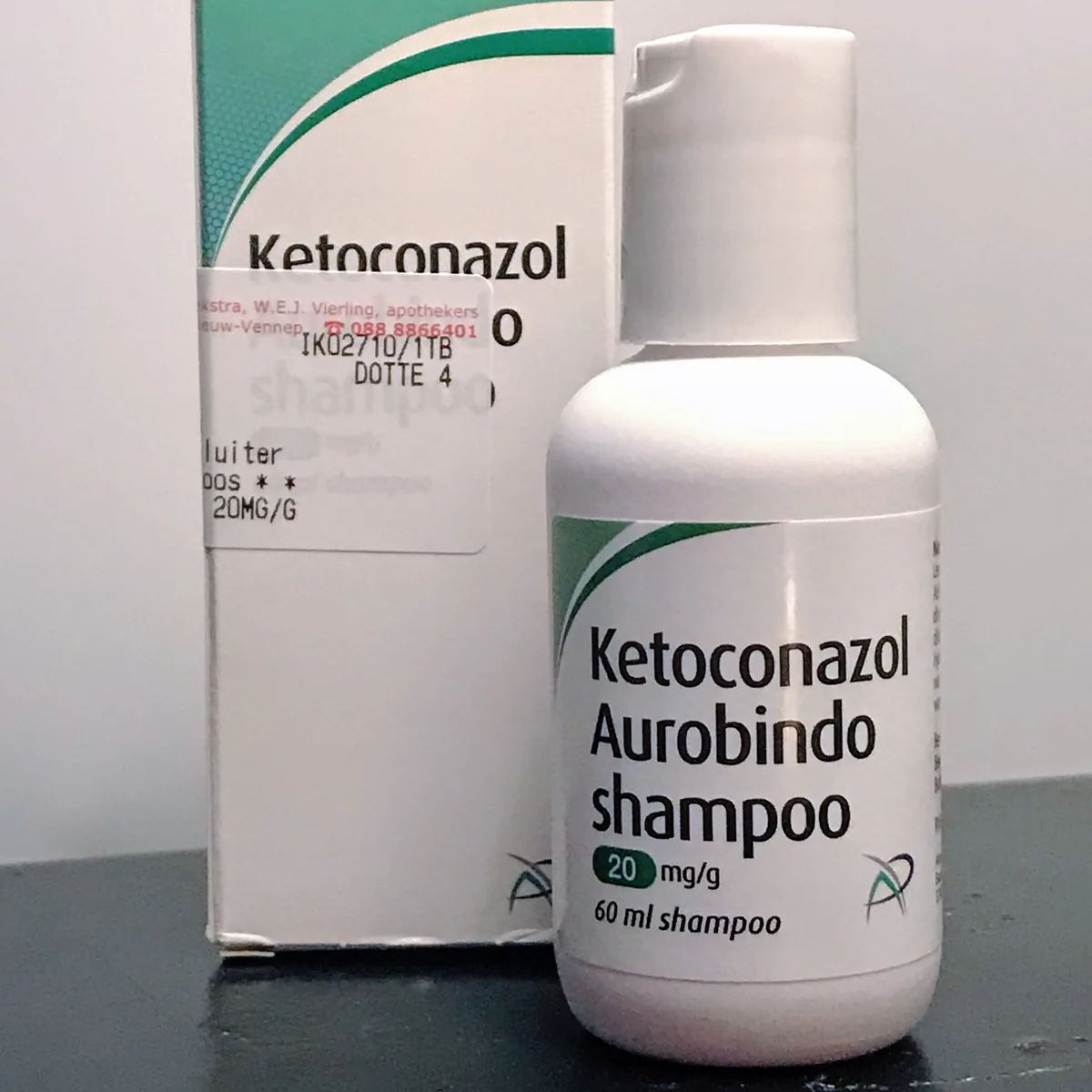 A white bottle of Ketoconazol Aurobindo shampoo 20 mg/g, 60 ml, standing in front of its box