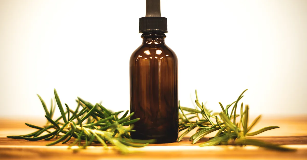 Rosemary oil in a brown glass dropper bottle, with fresh rosemary sprigs on either side