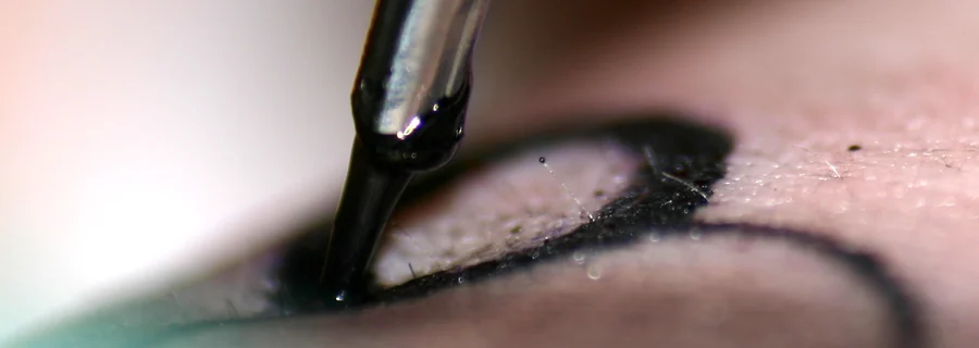 Close-up of a tattoo needle placing black ink in the skin