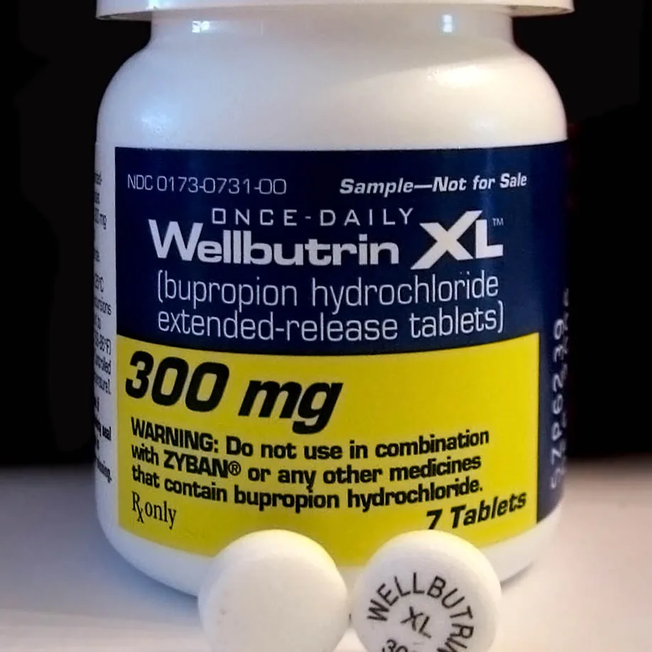 A bottle of once-daily Wellbutrin XL 300 mg bupropion hydrochloride extended-release tablets with two round white tablets in front