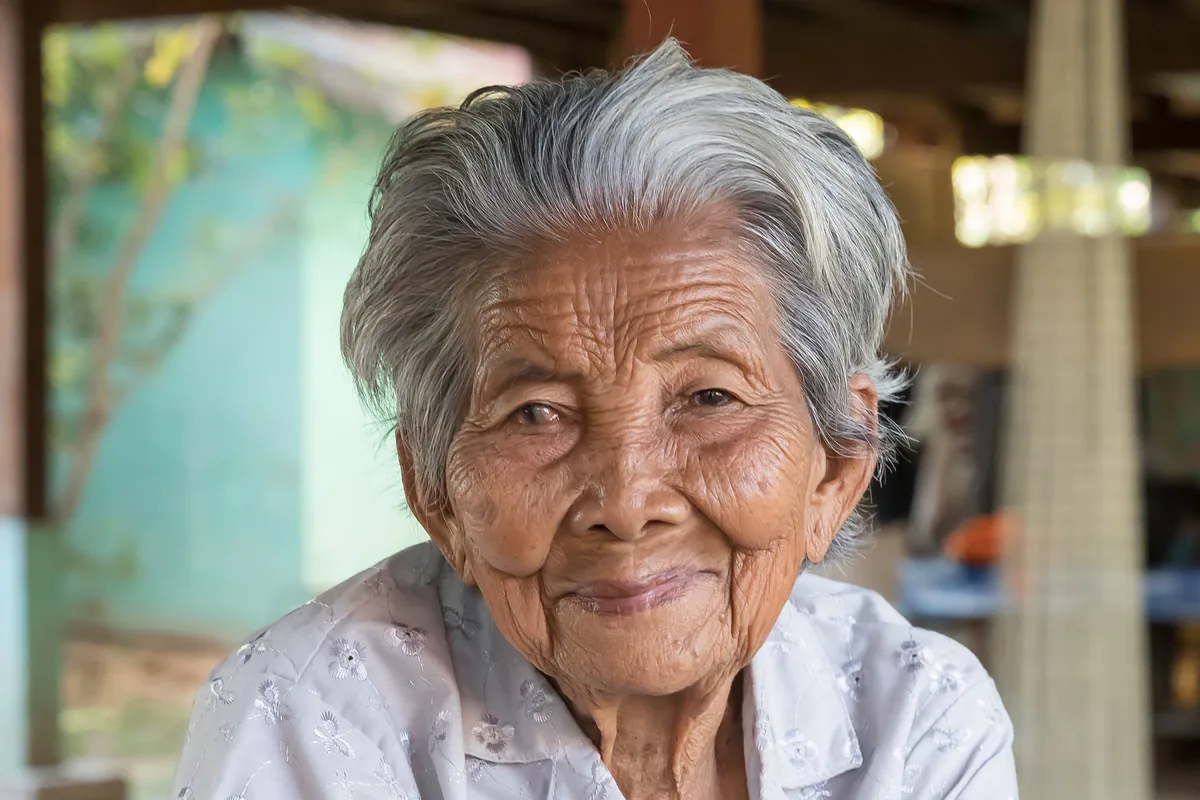 Smiling older woman with a full head of wavy white and gray hair swept back from her face