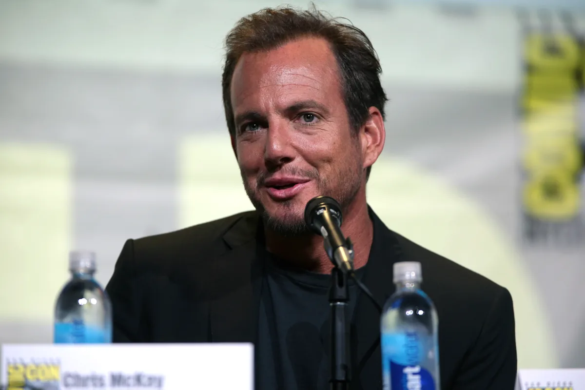 Will Arnett speaking at San Diego Comic-Con in 2016, with longer hair swept up and to the side and a full beard